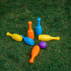 Children's set to play bowling on green grass. Ball and colored pins. Kid's game toy. Bowling colorful plastic pins. Active and interesting childhood concept.