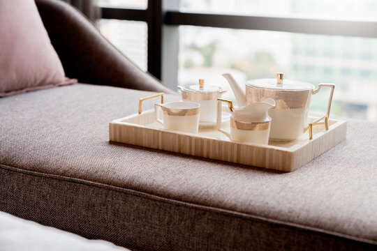 set of tea or coffee with small teapot on wooden trayon daybed sofa with room interior background  in morning time home decor concept