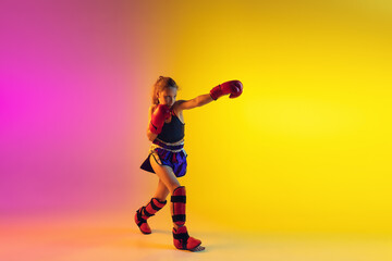 Fototapeta na wymiar Little caucasian girl, kick boxer on gradient background in neon light, active and expressive. Concept of motion, action, motivation, childhood. Training winner, emotional. Sales, ad, copyspace.