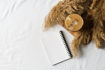 Ice coffee and dry flower or grass on white texture background