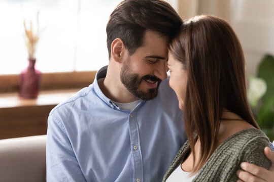 Close up young loving couple touching foreheads with closed eyes, beautiful woman and man enjoying intimate tender moment together, happy wife and husband cuddling, expressing love and care