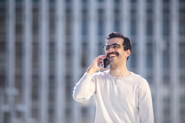 Joven trabajador ejecutivo feliz hablando por el teléfono móvil en el descanso del trabajo con...