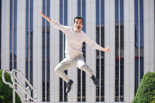 Joven exitoso en el entorno laboral muy feliz saltando para celebrar un ascenso en el trabajo