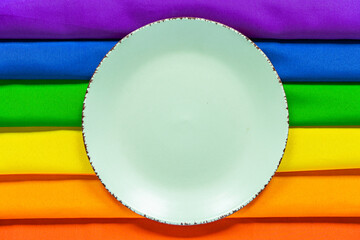 White plate on the background of a rainbow LGBT symbol close - up for design. Lunch dish on a rainbow background.