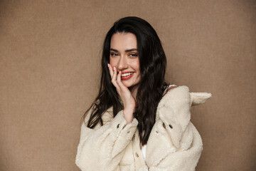 Photo of joyful young woman in jacket smiling and looking at camera
