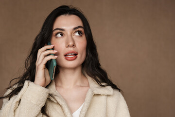 Photo of beautiful young brunette woman in jacket talking on cellphone