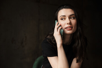 Photo of beautiful woman sitting on chair and talking on cellphone