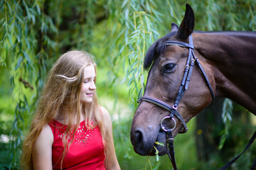 outdoor portrait of young beautiful woman with horse. Against the background of a tree