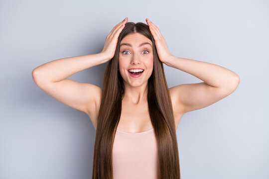 Photo of attractive shocked lady looking mirror ideal neat long healthy hairstyle after salon procedure arms on head not believe eyes wear beige singlet isolated grey color background