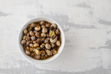 boiled snails in white bowl on ceramic background