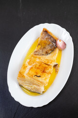 fried cod fish with garlic and olive oil on white dish