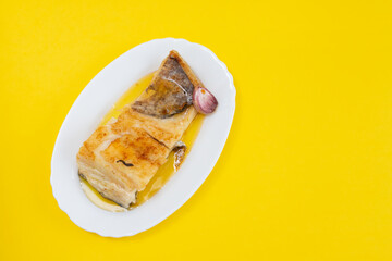 fried cod fish with garlic and olive oil on white dish