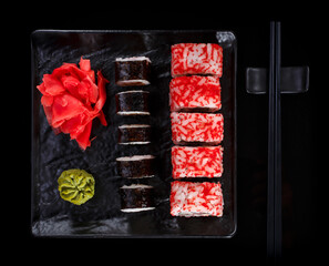Japanese sushi on a dark stone background. Sushi set with ginger, wasabi and soy sauce. Serve with chopsticks.