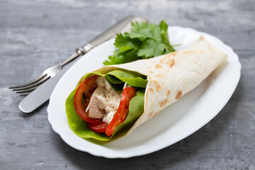 chicken and salad tortilla wraps on white dish on ceramic background
