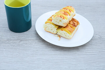 Loaves of cheese bread and mug of coffee on wooden table 