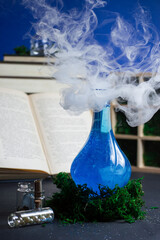 Still life of magical glass bottle with blue potion and thick smoke