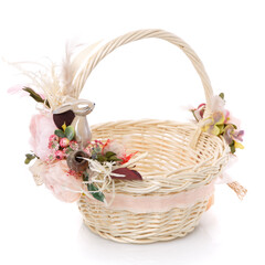 Fototapeta na wymiar Wicker basket of natural vines with floral decor and ribbons on white background. The basket decor is made in delicate pink tones for Easter celebration.