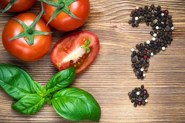 whole tomatoes on a branch and slices, Basil leaves on a wooden surface. ingredients: vegetables, spices, greens. background. menu, recipe.