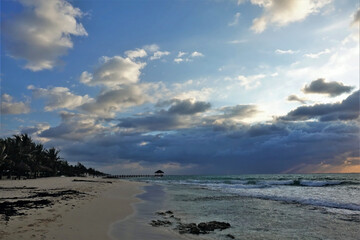 Dawn on the Caribbean. The rising sun painted the clouds orange. Waves leave lacy foam on a sandy...