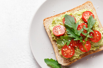 Avocado rye bread toast with cherry tomatoes and arugula