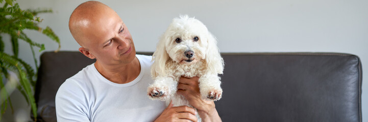Handsome man with cute white dog at home