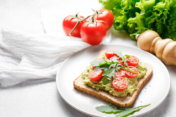 Avocado rye bread toast with cherry tomatoes and arugula