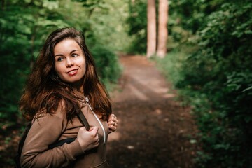 A young girl with long hair walks in the woods. Hiking with tents or traveling to natural places