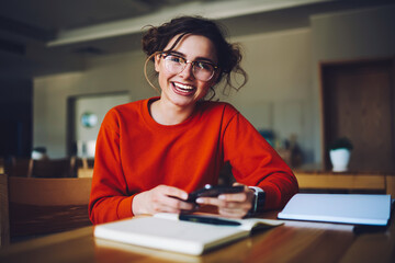 Charming emotional hipster girl satisfied getting job offer on email box, smiling attractive student feeling happy about receiving money transfer using smartphone for checking online banking