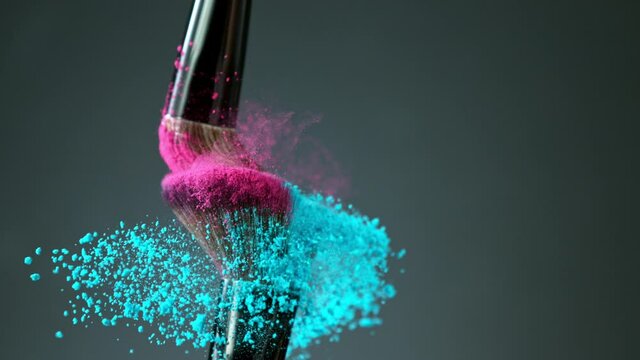 Makeup brushes touch each other on dark background and small particles of cosmetics, super slow motion, 1000 fps.