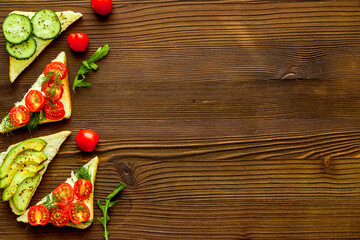 frame of avocado sandwiches on wooden kitchen table top view copy space
