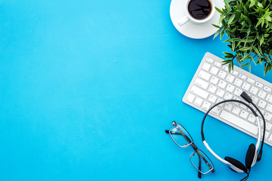 Office workplace. Headphones, computer keyboard on blue background top view copy space