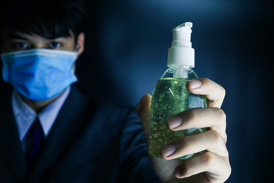 Businessman with mask holding bottle of hand sanitizer
