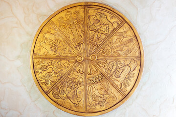 Obraz na płótnie Canvas Round decorative ornament hangs on the wall. Golden round decoration