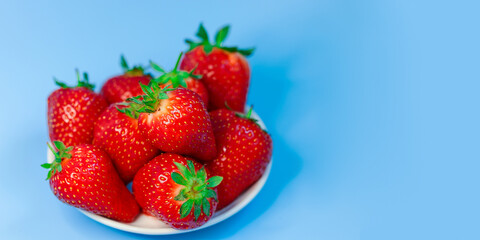 Fresh, ripe, delicious strawberries in a white Cup on a blue background. Free space for text. Background