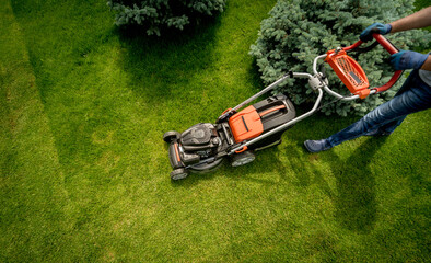 Gardener mowing the lawn. Landscape design. Green grass background - obrazy, fototapety, plakaty