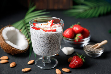 Chia seeds pudding with strawberries and coconut chips in glass.