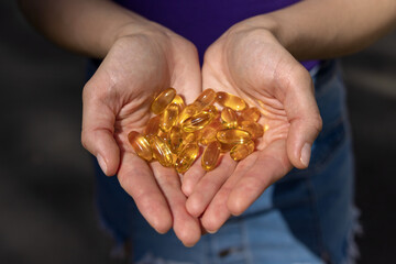 A handful of vitamin d capsules are in women's hands. Blurred background