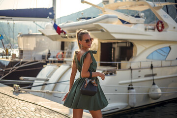 A beautiful woman in a fashionable summer dress and stylish accessories walks in the summer along...