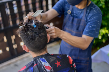 Asian businessman making haircut at home garden. Social distancing and New normal lifestyle.
