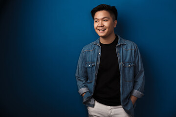 Image of pleased handsome asian man smiling and looking aside