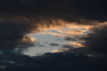 Naklejka na ściany i meble cielo azul con nubes grises y negras en puesta de sol al atardecer