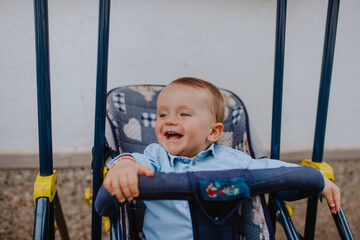 A beautiful caucasian child in a stroller in the yard