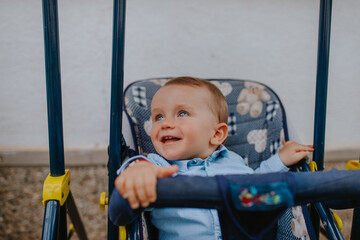 A beautiful caucasian child in a stroller in the yard