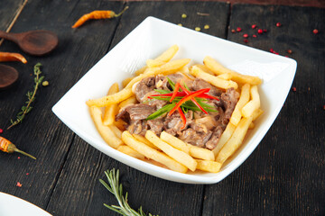 Fried potatoes with beef meat in a white plate
