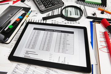 Top view of office employee's desk - work with tablet pc computer and financial reports, analysis and accounting, tables and graphs, various office items for bookkeeping