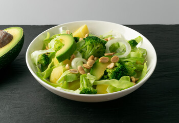 Green Salad with Avocado, Cucumber and Nuts on White Plate