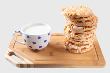 Healthy eating - corn crisps and milk. Corn crisps and a mug with milk on a wooden board isolated on a light background.