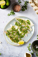 Marinated sea bass fish fillets in fresh cilantro herbs and lime top view with olive oil, garlic and salt