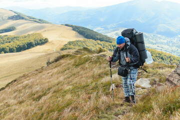 A middle-aged man with a large backpack hiking in the mountains.