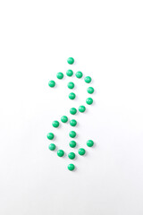 Tablets forming dollar sign. Symbol of American currency from green pills. High cost of medicine and healthcare